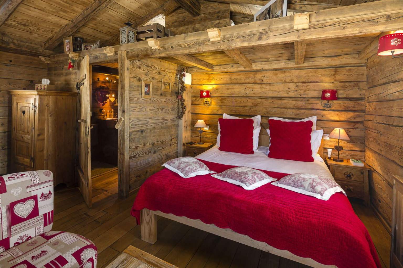 Chambre cosy avec des draps rouges et une décoration en bois au Manoir des Montagnes, hôtel de charme dans le Jura, aux Rousses